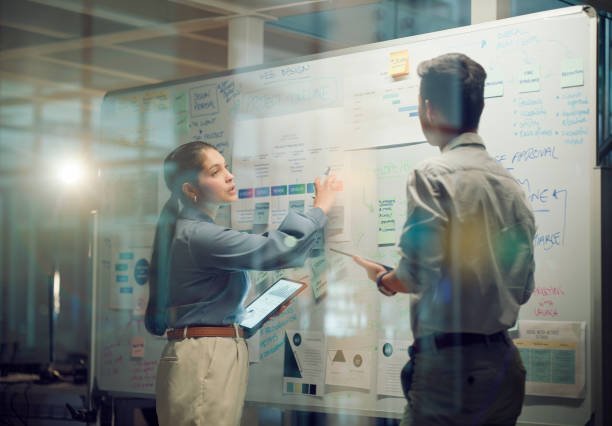 Window, teamwork and whiteboard for brainstorming in meeting, business people with tablet and digital notes with agenda storyboard. Information, people with research and calendar for project schedule